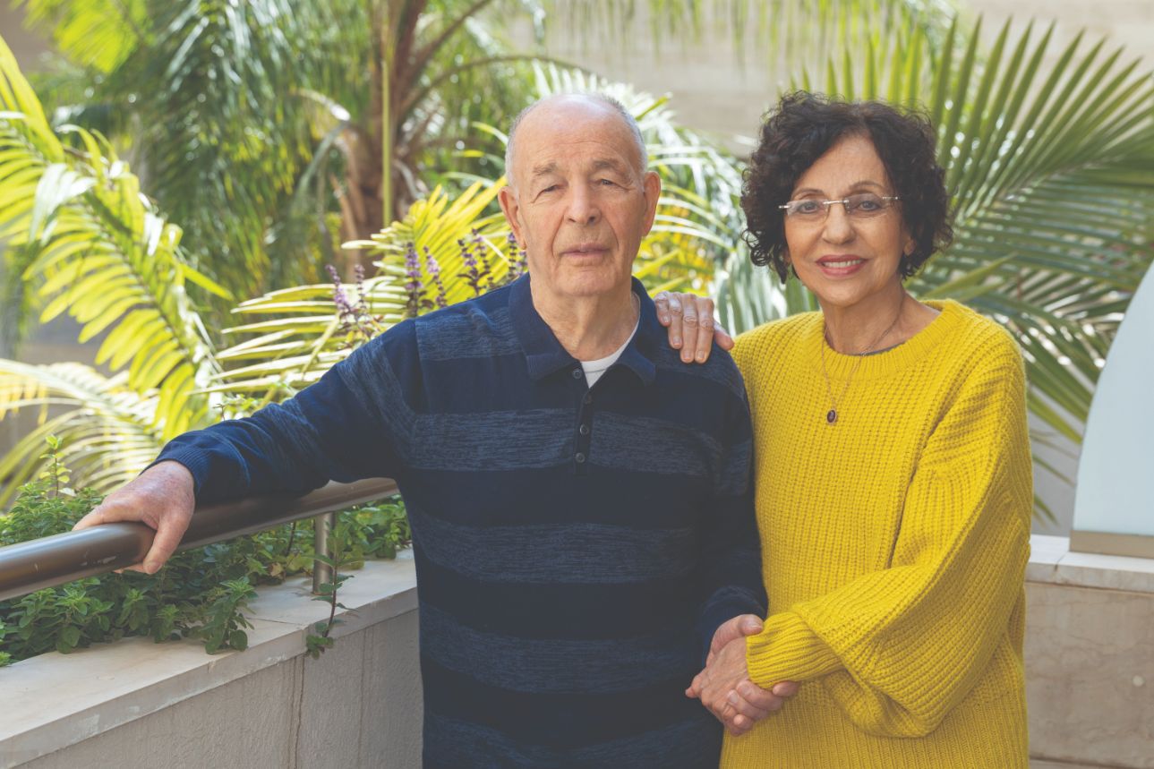 אביבה ואריה פאר זוג מבוגרים מחזירים ידיים ומחייכים