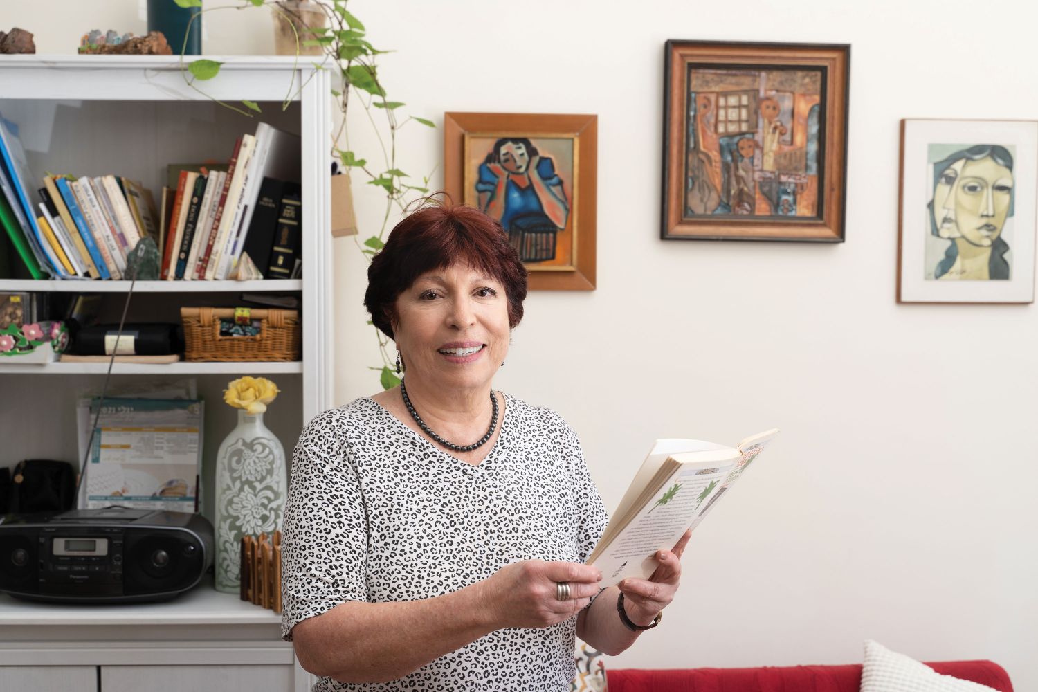 יהודית שניידר דיירת מבוגרת בגיל השלישי של דיור מוגן עד 120 בראשון לציון מחזיקה ספר ונמצאת בחדר שלה