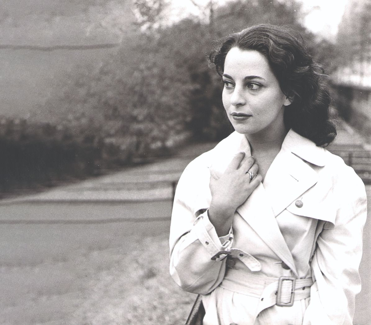 צילום בשחור לבן של דינה דורון בצעירותה לובשת מעיל ומחזיקה את הצווארון שלו 