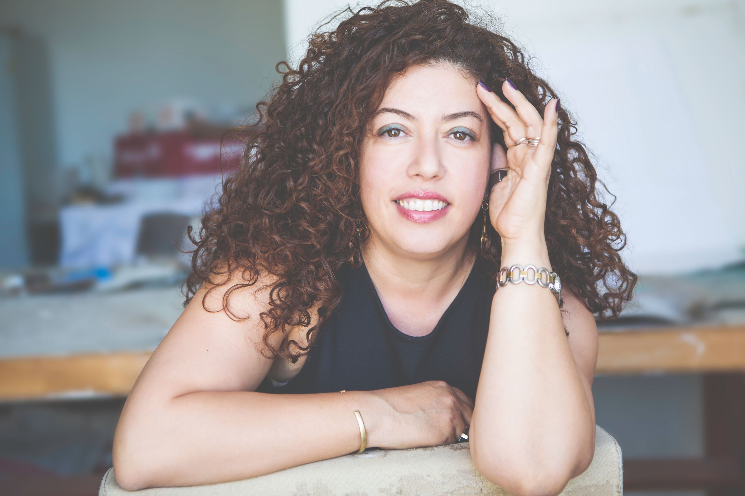 מפיקת האופנה גילי סיוון-כהן משעינה את הראש על כף היד ומחייכת 